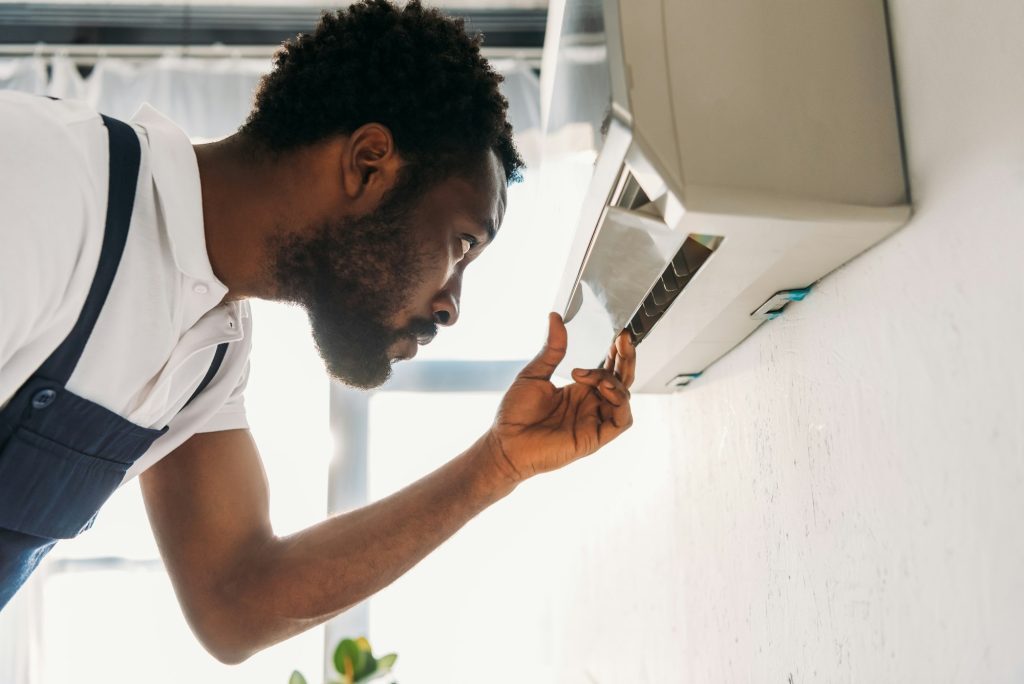 concentrated-african-american-repairman-looking-at-broken-air-conditioner.jpg
