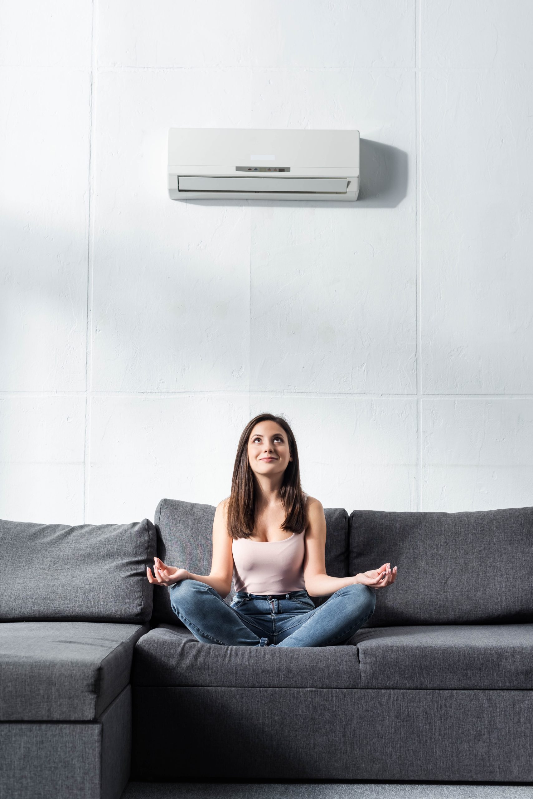 attractive and smiling woman in lotus pose sitting on sofa